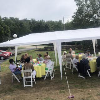 A gathering under a large white tent, with guests seated at tables for an outdoor event.