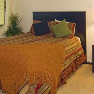 A cozy bedroom with a neatly made bed, accent pillows, and warm lighting.