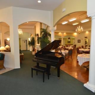 A cozy restaurant interior featuring a grand piano and elegantly set dining tables.