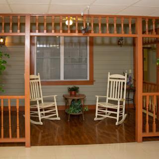 A cozy seating area featuring two rocking chairs surrounded by a wooden framework and indoor plants.