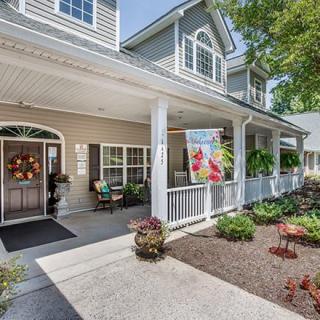 A charming residential house with a spacious front porch and well-maintained garden.