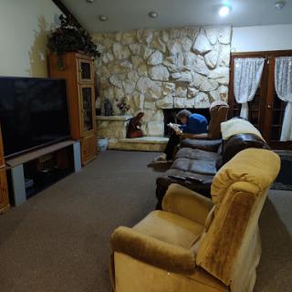 A cozy living room featuring a stone wall, comfortable seating, and a television.