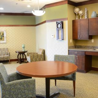 A cozy lounge area with a round table, two chairs, and a kitchenette.