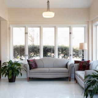 A bright and minimalist living room with large windows, a comfortable sofa, and potted plants.