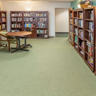 A cozy library room with bookshelves lining the walls and a round table with chairs in the center.