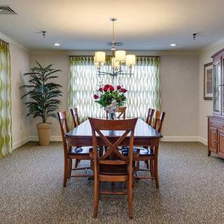 Elegant dining room with a wooden table and chairs, featuring a chandelier and decorative elements.