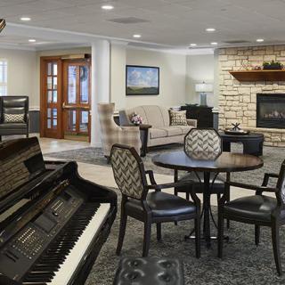 A cozy living room with a piano, seating area, and a fireplace.