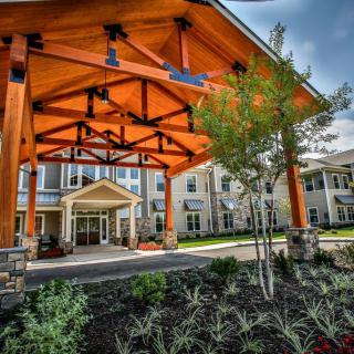 A modern building with a prominent wooden entrance and landscaped surroundings.