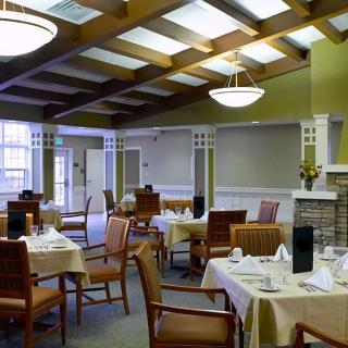 A well-decorated dining room with neatly arranged tables and chairs, featuring elegant lighting and interior design.
