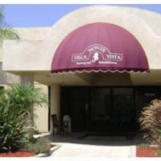 Entrance to a building with a maroon awning and landscaped plants.