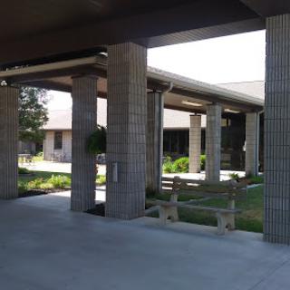 A view of a modern architectural structure featuring concrete pillars and landscaped areas.