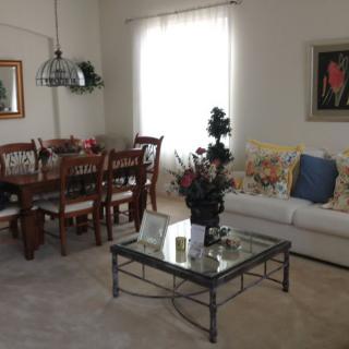 A cozy living room with a sofa and dining area, featuring decorative elements and natural light.