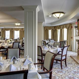 An elegant dining room with neatly arranged tables and chairs, featuring classic decor and warm lighting.