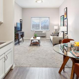 A cozy living room with modern furniture, a television, and a dining area.
