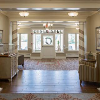A spacious and elegantly decorated lobby area with comfortable seating, a chandelier, and large windows allowing natural light to fill the space.
