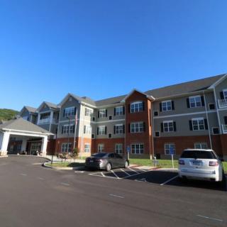 A residential building with a parking lot and cars under a clear blue sky.
