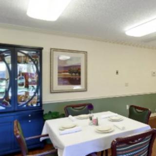 A neatly set dining room with a table, chairs, and a china cabinet.