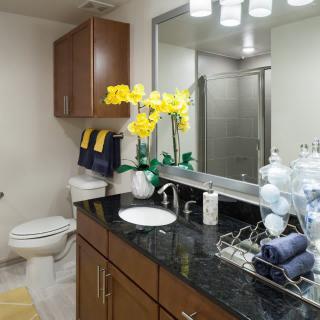 A modern bathroom with a sleek countertop, mirror, and decorative flowers.