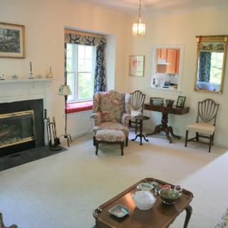A cozy living room with traditional decor, featuring a fireplace, armchair, and coffee table.