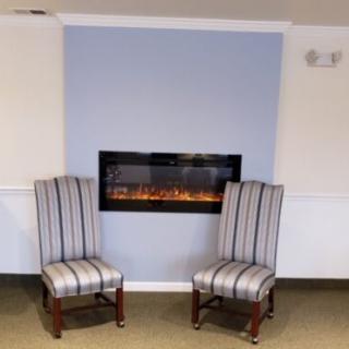 A cozy seating arrangement with two striped chairs in front of a modern fireplace.