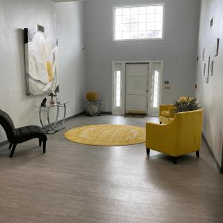 A modern living room with gray walls, featuring yellow accents, a round rug, and stylish artwork.