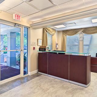 A well-lit office reception area with a desk and glass doors.