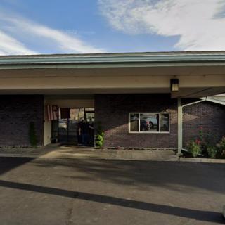 A building entrance with a small parking area and a partly cloudy sky.