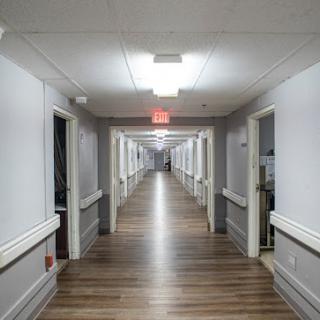 A long, well-lit hallway lined with doors on both sides.