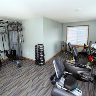 A well-equipped home gym featuring exercise bikes, a strength training machine, and free weights.