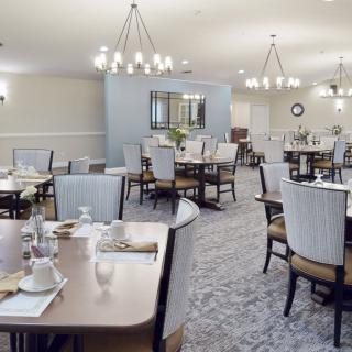 Elegant dining room with neatly arranged tables and chairs under stylish chandeliers.