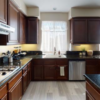 A modern kitchen featuring dark wood cabinets and stainless steel appliances.