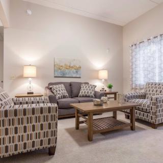 A cozy living room with sofas, armchairs, a wooden coffee table, and warm lighting.