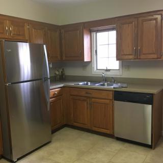 A kitchen with wooden cabinets and stainless steel appliances, including a refrigerator and dishwasher.