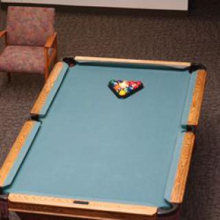 A pool table with a racked set of billiard balls in a cozy game room.