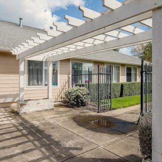 A sunny patio area with a pergola and well-maintained garden outside a house.