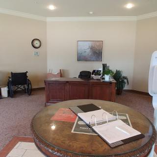 An office interior with a desk, wheelchair, and documents on a table.