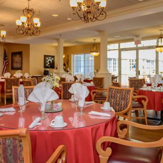 Elegantly set dining room with red tablecloths and chandeliers.
