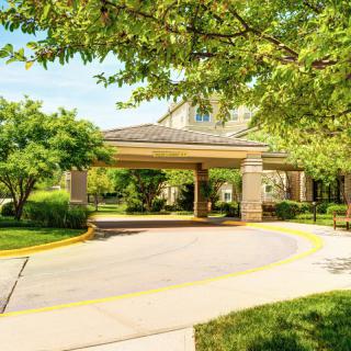 A building entrance surrounded by greenery and a curved driveway.
