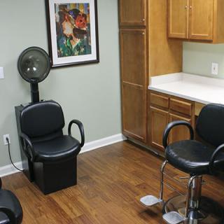 A well-organized beauty salon interior featuring chairs, a hair dryer station, and storage cabinets.
