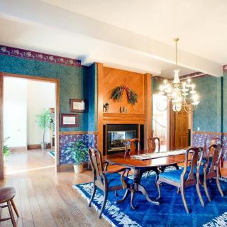 A traditional dining room with a chandelier, wooden table and chairs, a fireplace, and vibrant blue accents.