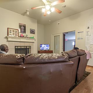 Two people sitting on a sofa in a cozy living room watching television.