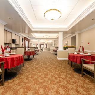 A spacious dining area with tables covered in red tablecloths and a warm, inviting atmosphere.