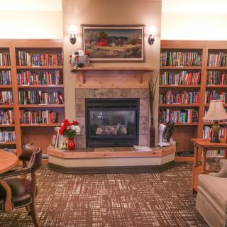 A cozy library interior featuring bookshelves, a fireplace, and comfortable seating.