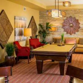 A stylish living room featuring a billiard table, red chairs, and elegant decor.