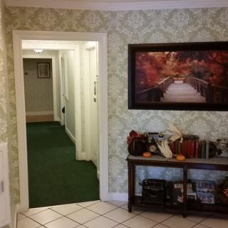 A cozy hallway with a green carpet, adorned with artwork and home decor elements.