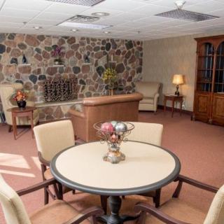 A cozy living room with a round table, chairs, and a stone accent wall.
