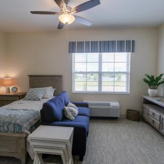 A cozy bedroom featuring a bed, sofa, and ample natural light from a large window.