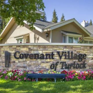 Entrance sign for Covenant Village of Turlock, surrounded by a landscaped area with flowers.