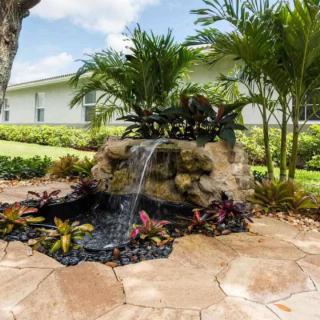 A beautifully landscaped garden featuring a small waterfall surrounded by tropical plants.