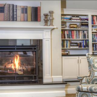 A cozy living room with a lit fireplace and a well-stocked bookshelf.